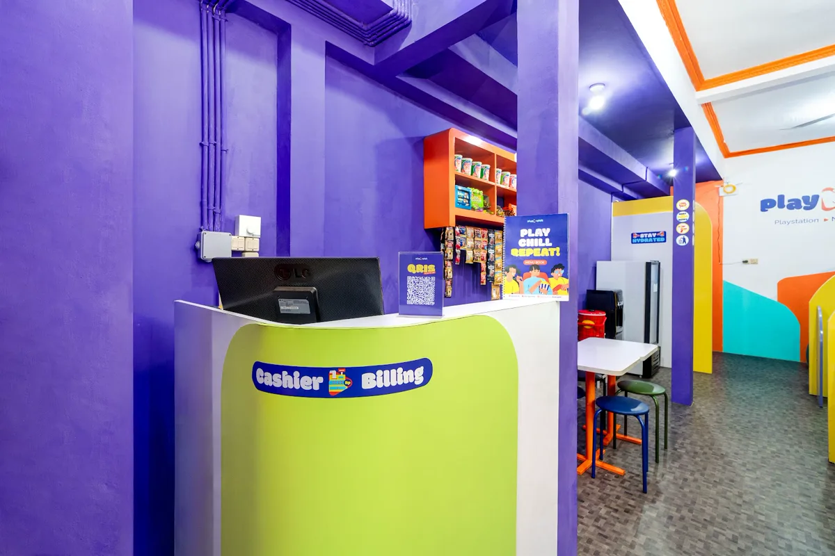 Meja kasir Play N Chill dengan dinding ungu dan etalase makanan ringan